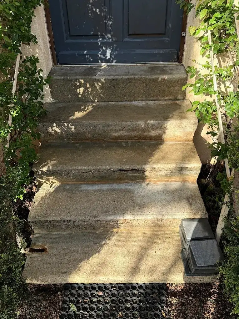 Escalier extérieur en pierre devant une porte bleue